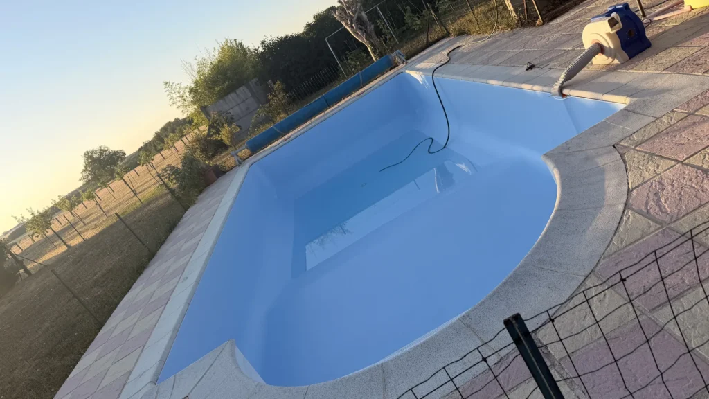 Liner bleu fraîchement posé sur une piscine à escalier roman, souffleur en marche, chantier près d'Étampes